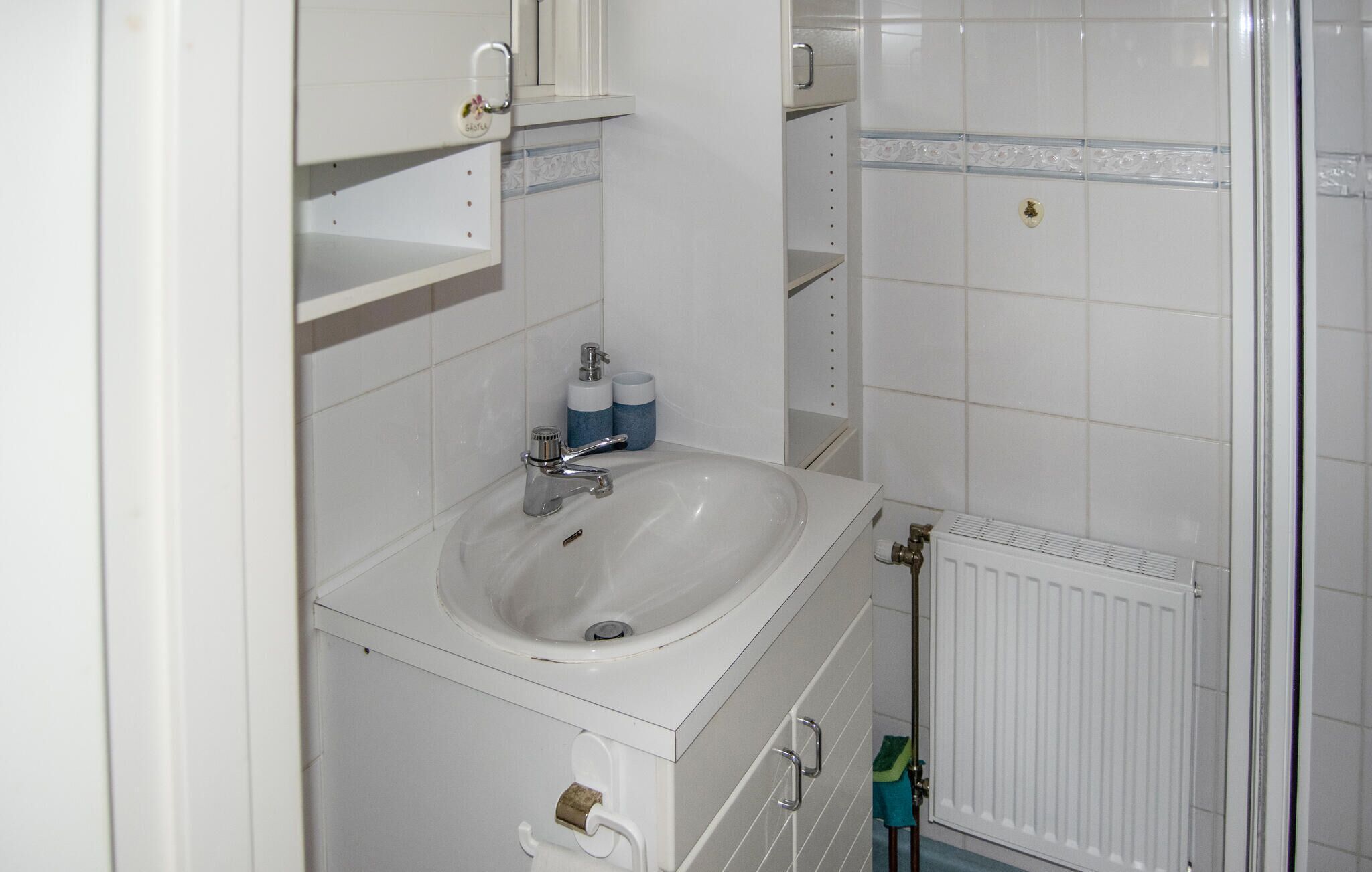 Et badeværelse med en hvid vask, et spejl og en radiator.