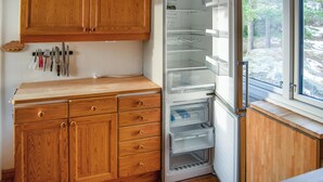 A kitchen with wooden cabinets, a built-in refrigerator, and a window with a view of trees. - Amazing home in åkersberga with WiFi (Åkersberga)