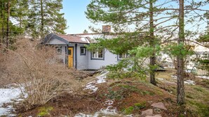A small, single-story house with a red-tiled roof, surrounded by trees and a snowy landscape. - Amazing home in åkersberga with WiFi (Åkersberga)