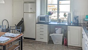 A compact kitchen with a microwave, a sink, and a trash bin. There is a window with a view of buildings outside. - Cozy home in Bastuträsk with WiFi (Bastuträsk)
