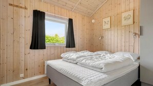 A bedroom with a bed, wooden walls, a window with curtains, and two framed pictures on the wall. - Pet-friendly home in Hejls with sauna (Hejls)
