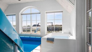 A swimming pool with a hot tub, large arched windows, and a view of the outdoors. - Pet friendly home in Ulfborg with sauna (Ulfborg)
