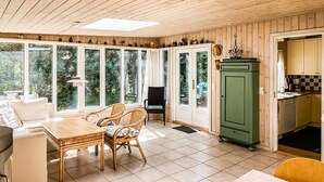 Una habitación acogedora con una mesa de comedor, sillas, un armario verde y ventanas amplias que dan al exterior.