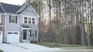 A two-story house with a stone facade, two garages, and a well-maintained lawn.