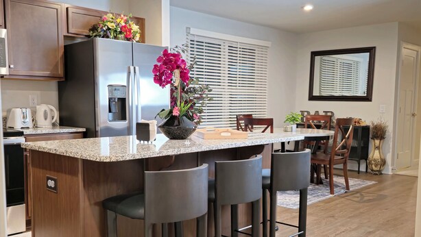 A modern kitchen with a granite countertop, stainless steel appliances, and a central island with bar stools.