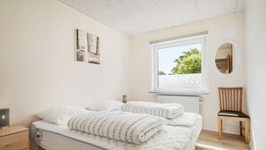 A bedroom with a bed, a bedside table, a chair, a window, and a wall-mounted mirror. - Nice home in Skjern with WiFi (Skjern)