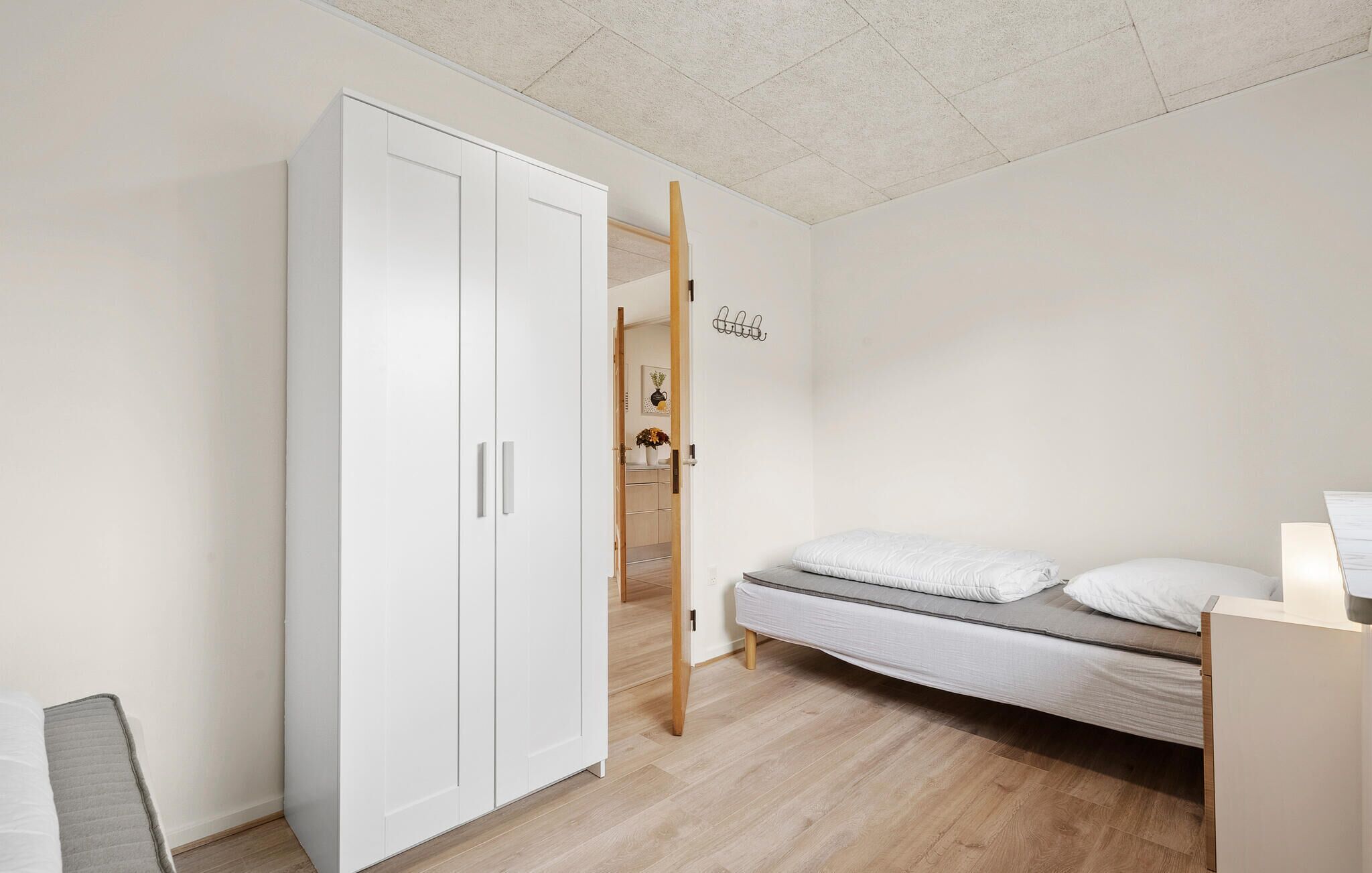 Een minimalistische slaapkamer met een enkel bed, een kledingkast en een klein bureau.