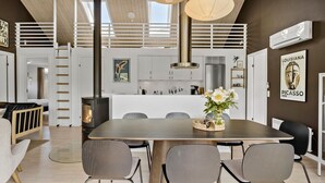A modern interior with a dining area, kitchen, and loft bedroom.