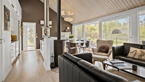 A spacious living area with a large window, a fireplace, and a dining area with a view of the outdoors.