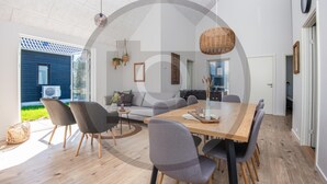 Uma sala de estar moderna com uma grande mesa de jantar de madeira, cadeiras estofadas cinzas e um lustre.