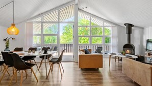 Um quarto espaçoso com teto alto, janelas amplas, lareira e móveis modernos.