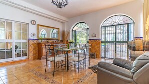 A spacious living area with a dining table, chairs, and a leather sofa. There are large windows and a view of the outdoors. - Pet friendly home in Guillena (Guillena)