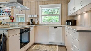 A modern kitchen with wooden cabinets, a built-in oven, a dishwasher, and a window with a view of greenery. - Nice home in Grevinge with WiFi (Grevinge)