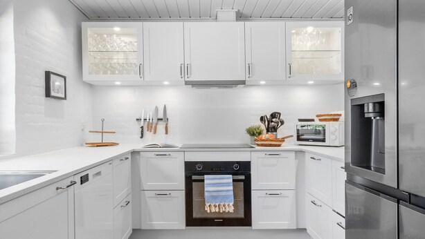 A modern kitchen with white cabinetry, a built-in oven, a microwave, and a stainless steel refrigerator. - Nice home in Ulfborg with sauna (Ulfborg)