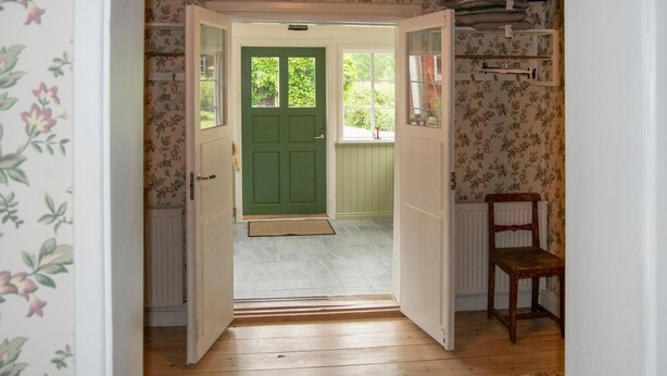 A hallway with a green door, wooden flooring, and floral wallpaper. - 3 bedroom beautiful home in Stallarholmen (Stallarholmen)