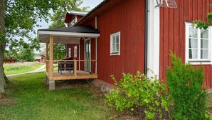 A red wooden house with a covered porch and a small table. - 3 bedroom beautiful home in Stallarholmen (Stallarholmen)