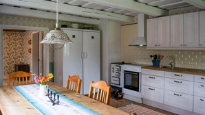 A kitchen with white cabinets, a wooden dining table with chairs, a hanging light fixture, and a stove. - 3 bedroom beautiful home in Stallarholmen (Stallarholmen)