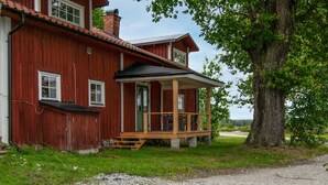 A red wooden house with a porch, a chimney, and a large tree nearby. - 3 bedroom beautiful home in Stallarholmen (Stallarholmen)
