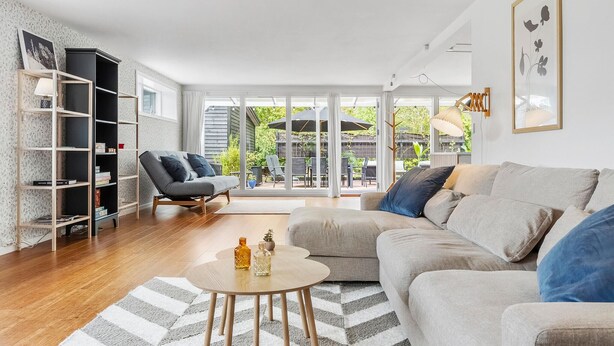A modern living room with a sofa, armchairs, a coffee table, and a bookshelf.