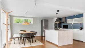 A modern kitchen with a central island, built-in appliances, and a large window providing natural light.