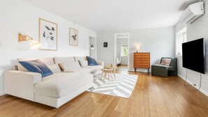 A modern living room with a sofa, a small table, a dresser, and a TV.