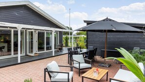 An outdoor patio area with a dining table, chairs, and a large umbrella.