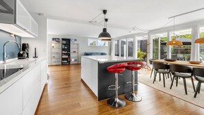 A modern kitchen with a central island, bar stools, and a dining area with chairs.