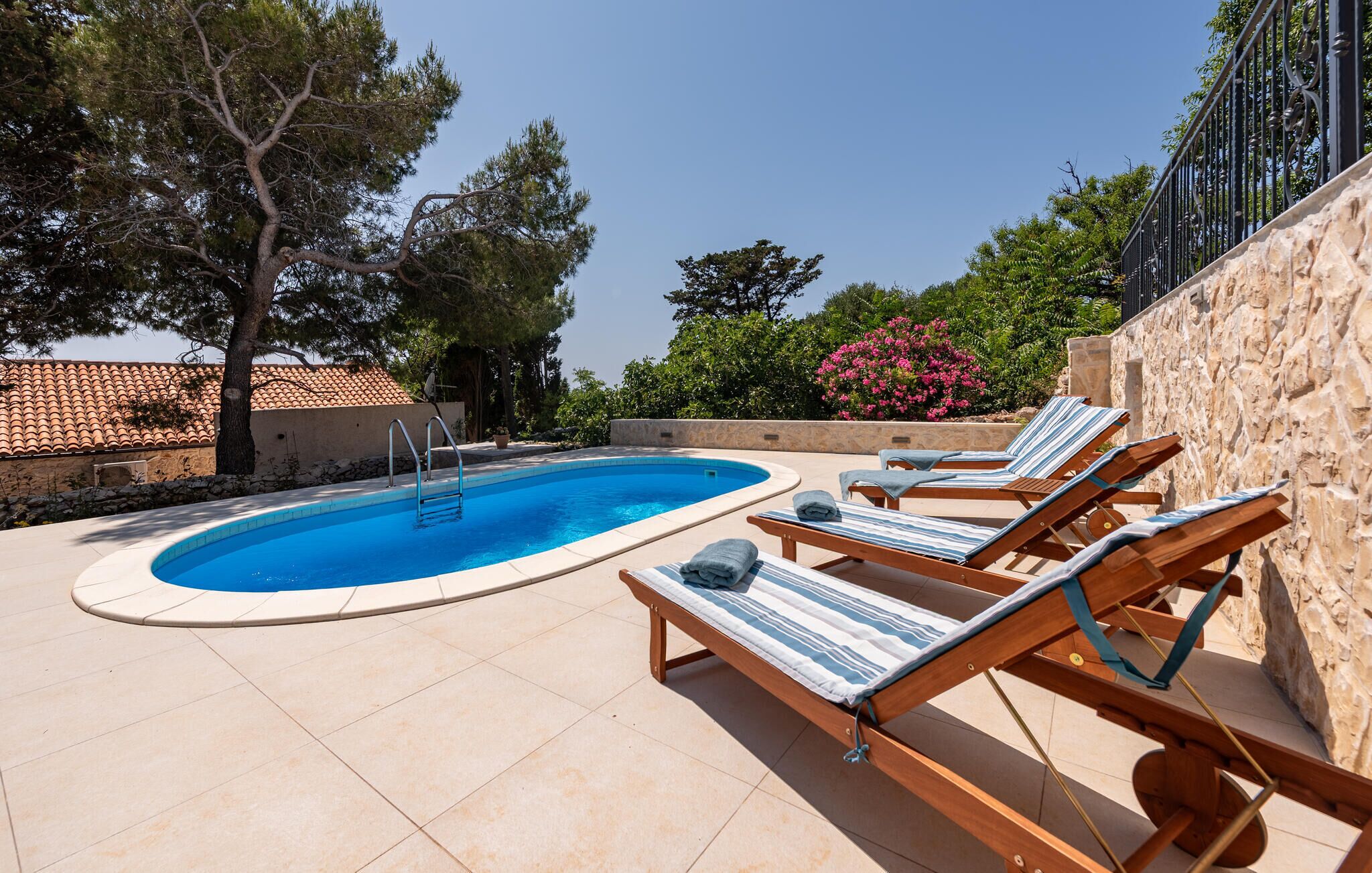 A swimming pool with lounge chairs and a stone wall.