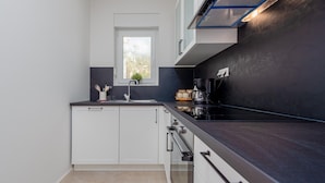A modern kitchen with white cabinets, a black countertop, and a window above the sink. - Lovely apartment in Povljana with WiFi (Povljana)