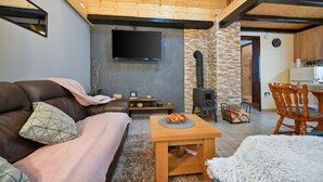 Ein gemütliches Wohnzimmer mit einer Ledersofa, einem Holztisch und einer Steinwand mit Kamin.
