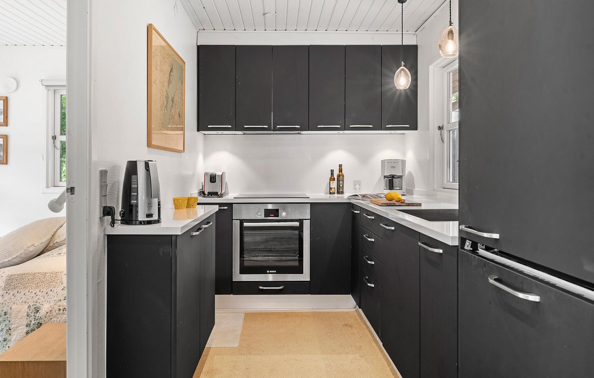 Een moderne keuken met zwarte kasten, een Bosch oven en een koffiezetapparaat.