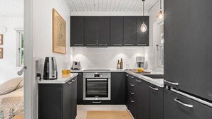 A modern kitchen with black cabinets, a Bosch oven, and a coffee maker. - Amazing home in Roslev with WiFi (Roslev)