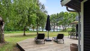 A wooden deck with outdoor seating and a view of a lake. - Amazing home in Roslev with WiFi (Roslev)