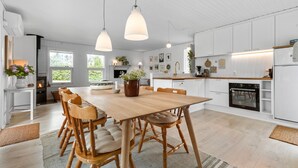 Eine moderne Küche mit weißen Schränken, einem Holztisch und Pendelleuchten.