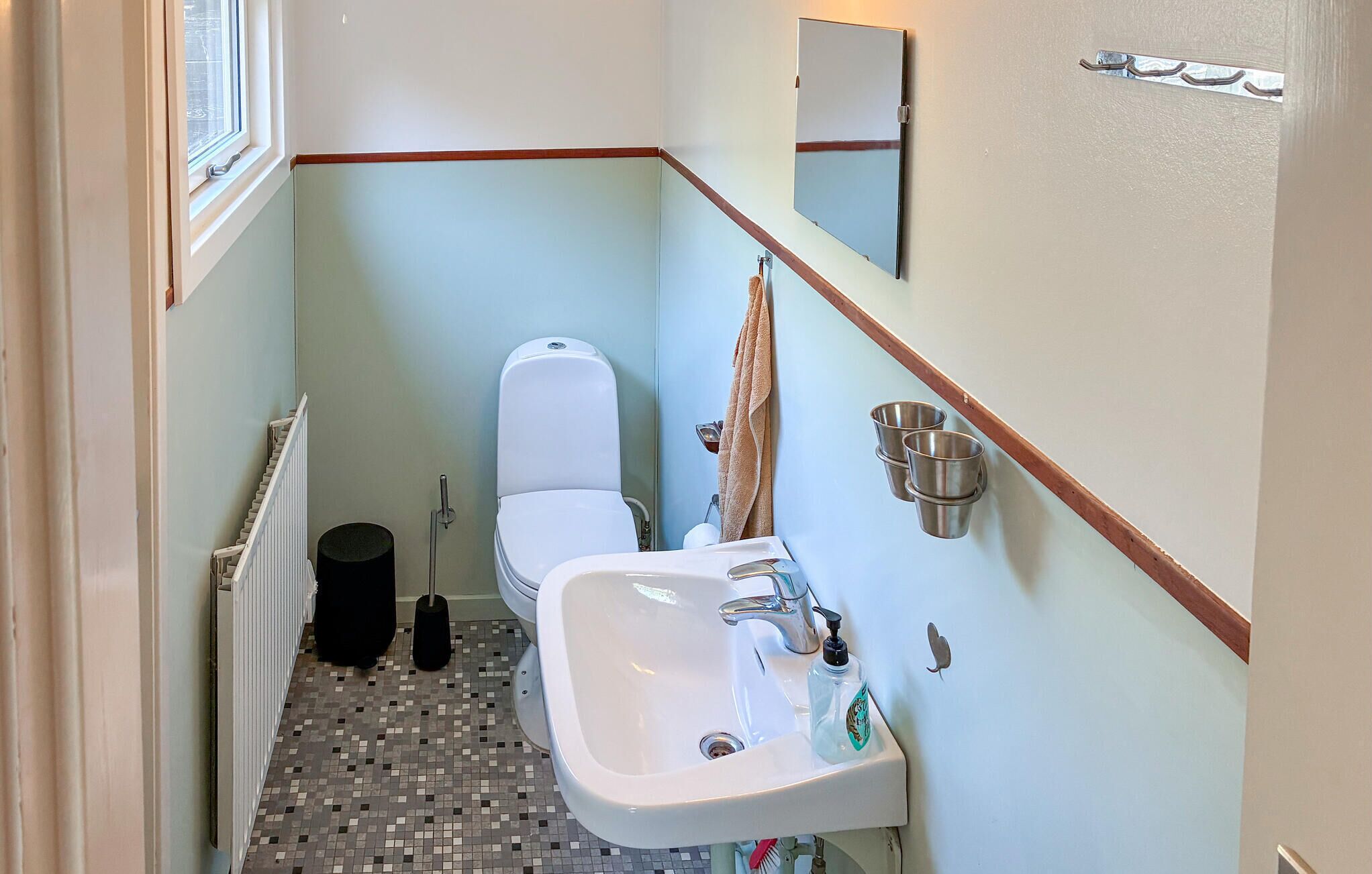 Un bagno stretto con il water, un lavandino e un piccolo cestino.