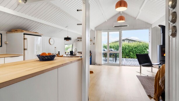 Eine moderne Küche mit einer Holz Arbeitsplatte, ein Essbereich mit Tisch und Stühlen sowie ein Gartenblick durch Glastüren.