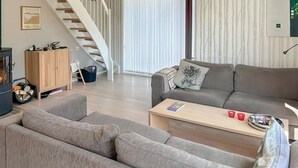 Una sala moderna con un sofá gris, un mueble de madera y una escalera.