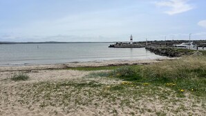 A coastal scene with a lighthouse, rocky shoreline, and boats docked near the pier. - 1 bedroom gorgeous home in åsa (Åsa)