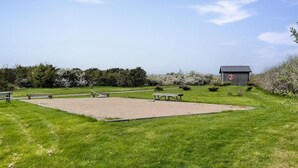 A grassy field with a gravel area, picnic tables, and a small wooden structure with a no parking sign. - 1 bedroom gorgeous home in åsa (Åsa)