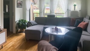 Una sala de estar con un sofá gris, una mesa redonda y una planta en maceta.
