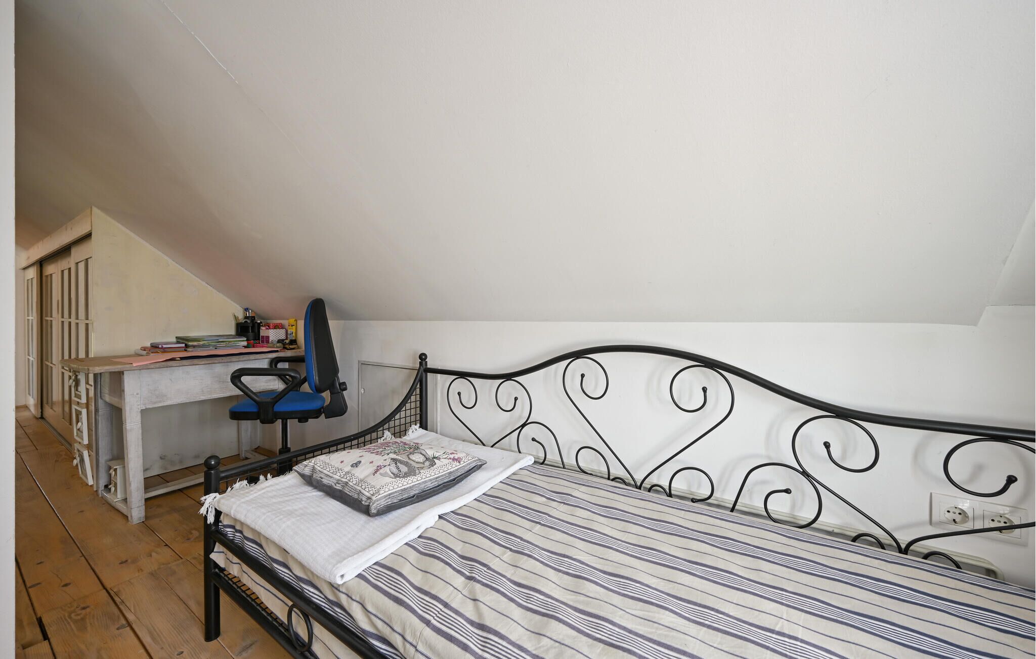 A bedroom with a bed, a desk, and a chair.