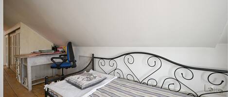 A bedroom with a bed, a desk, and a chair.