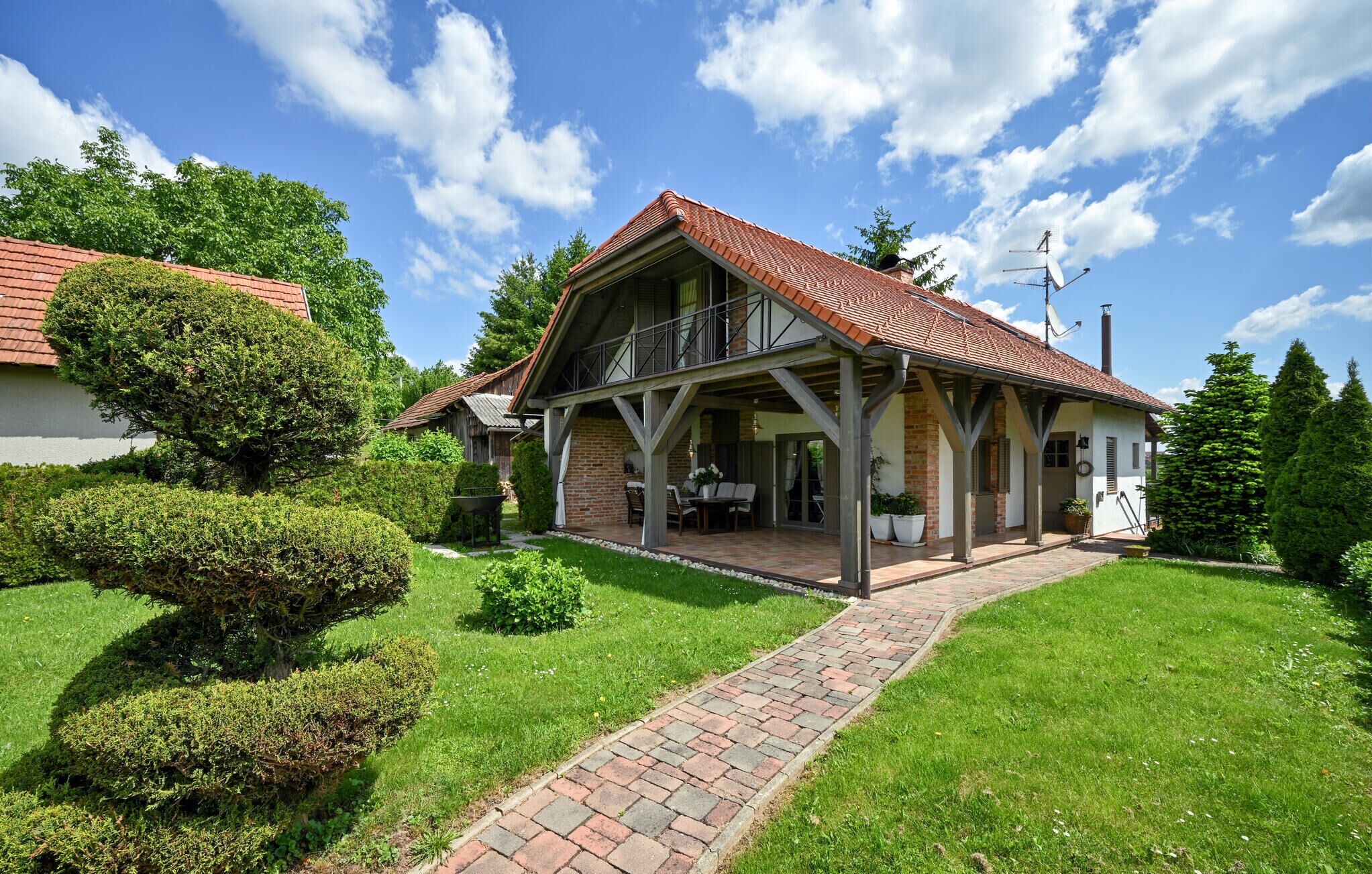 A two-story house with a brick facade, a balcony, and a covered patio area.