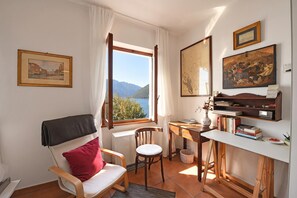 Une piĂšce avec un bureau, une chaise et une vue sur les montagnes par la fenĂȘtre.