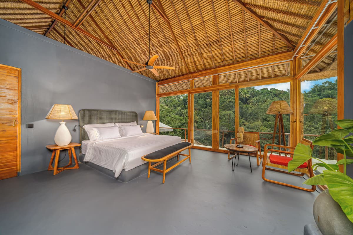 A spacious bedroom with a large bed, bedside lamps, a wooden bench, and a small table.