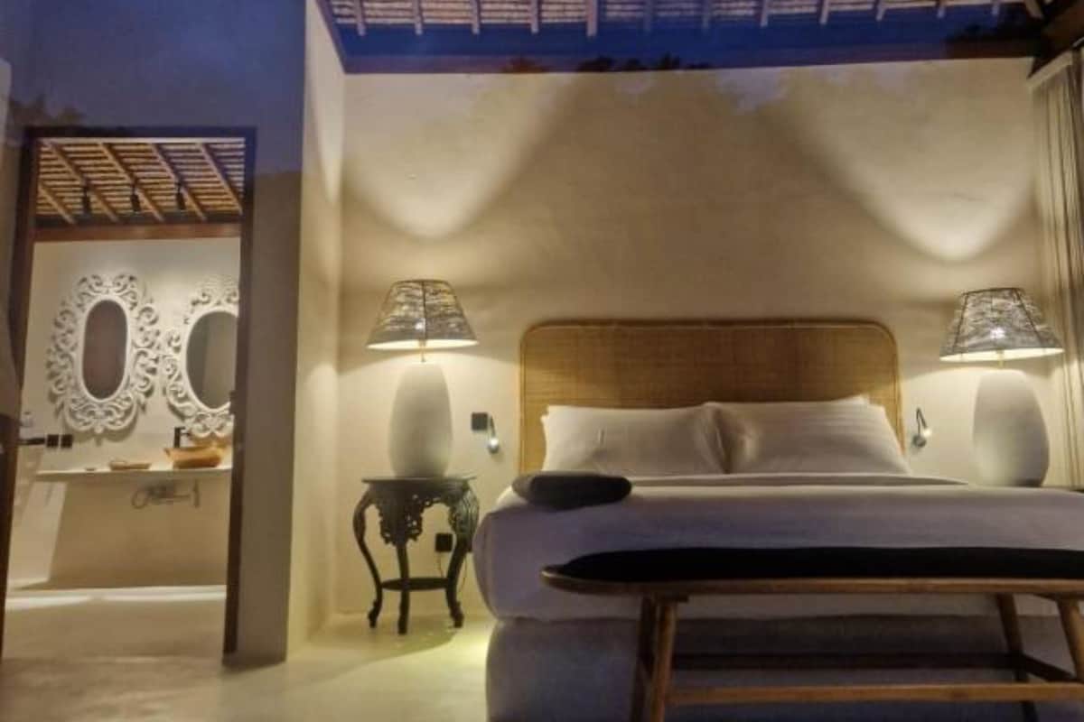 Une chambre à coucher comprenant un lit, deux lampes de chevet, une petite table et un miroir décoratif.