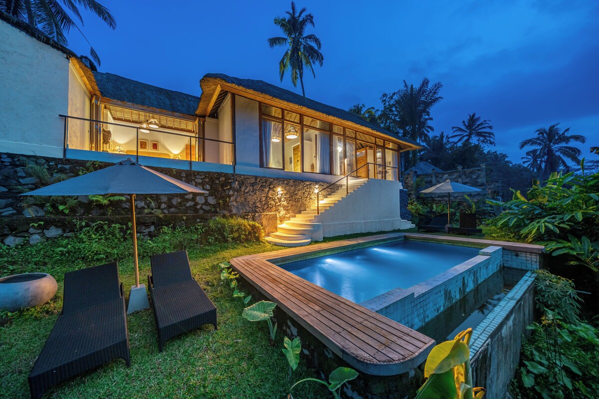 A modern house with a swimming pool, stone walls, and a staircase leading to the upper floor.
