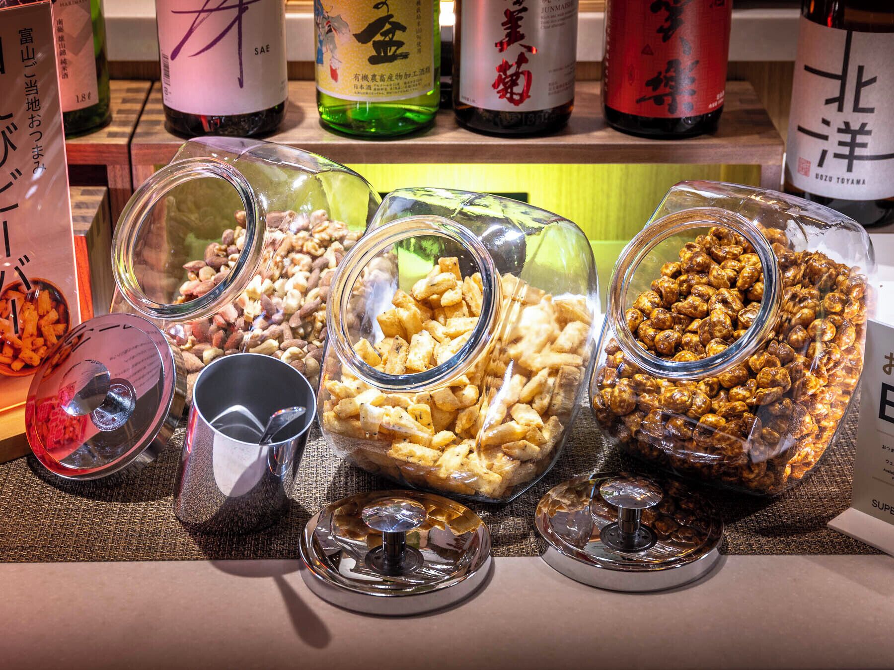 A selection of glass jars containing various snacks and nuts, with labels in a foreign language.
