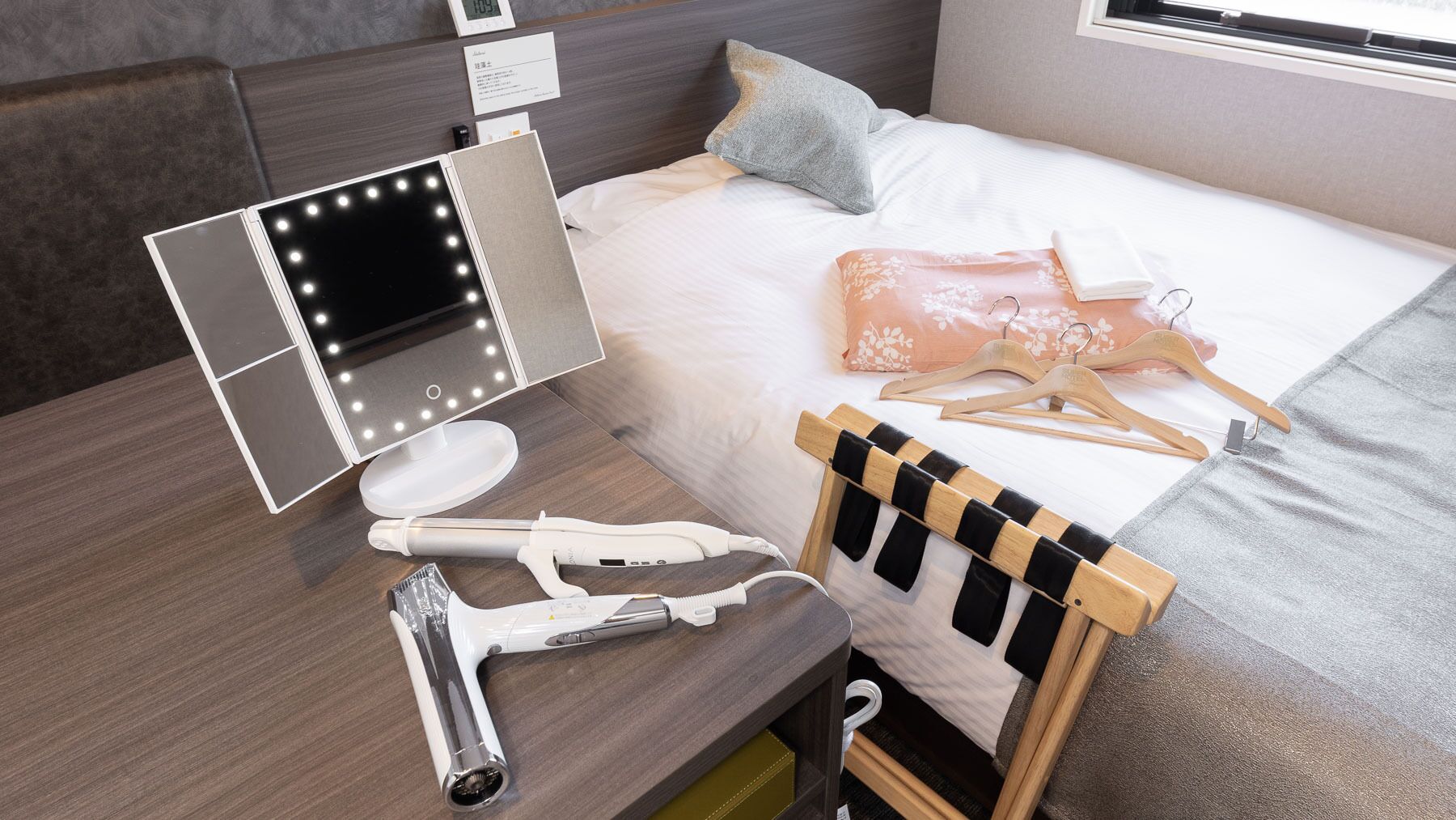 Una cama bien hecha con un edredón blanco y una almohada color melocotón.