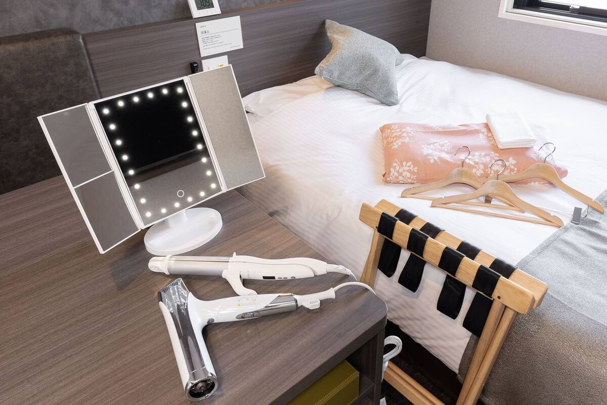 Una cama bien hecha con un edredón blanco y una almohada color melocotón.